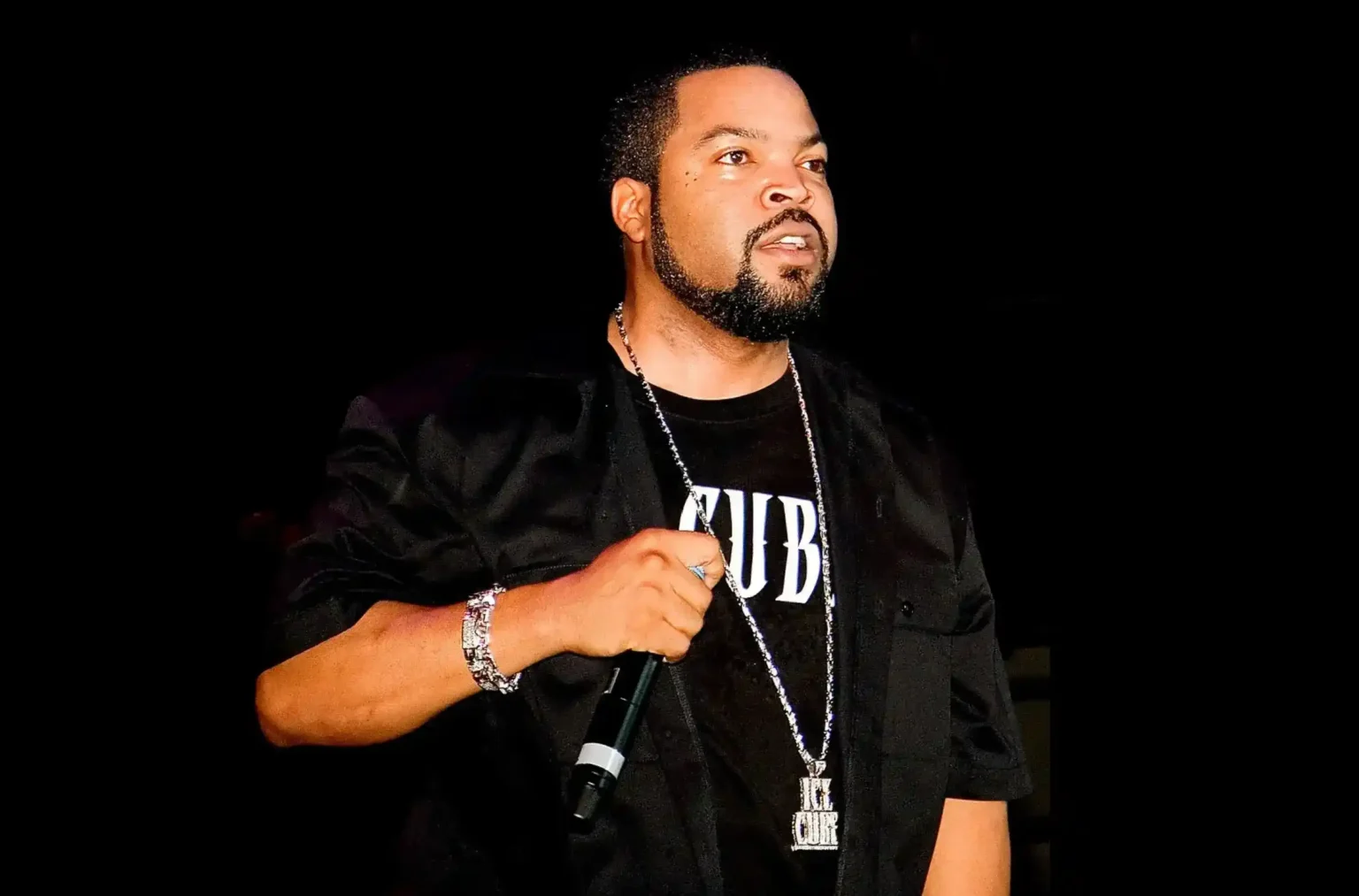 Image of Ice Cube, American rapper, songwriter, actor, and filmmaker, on stage holding a mic.