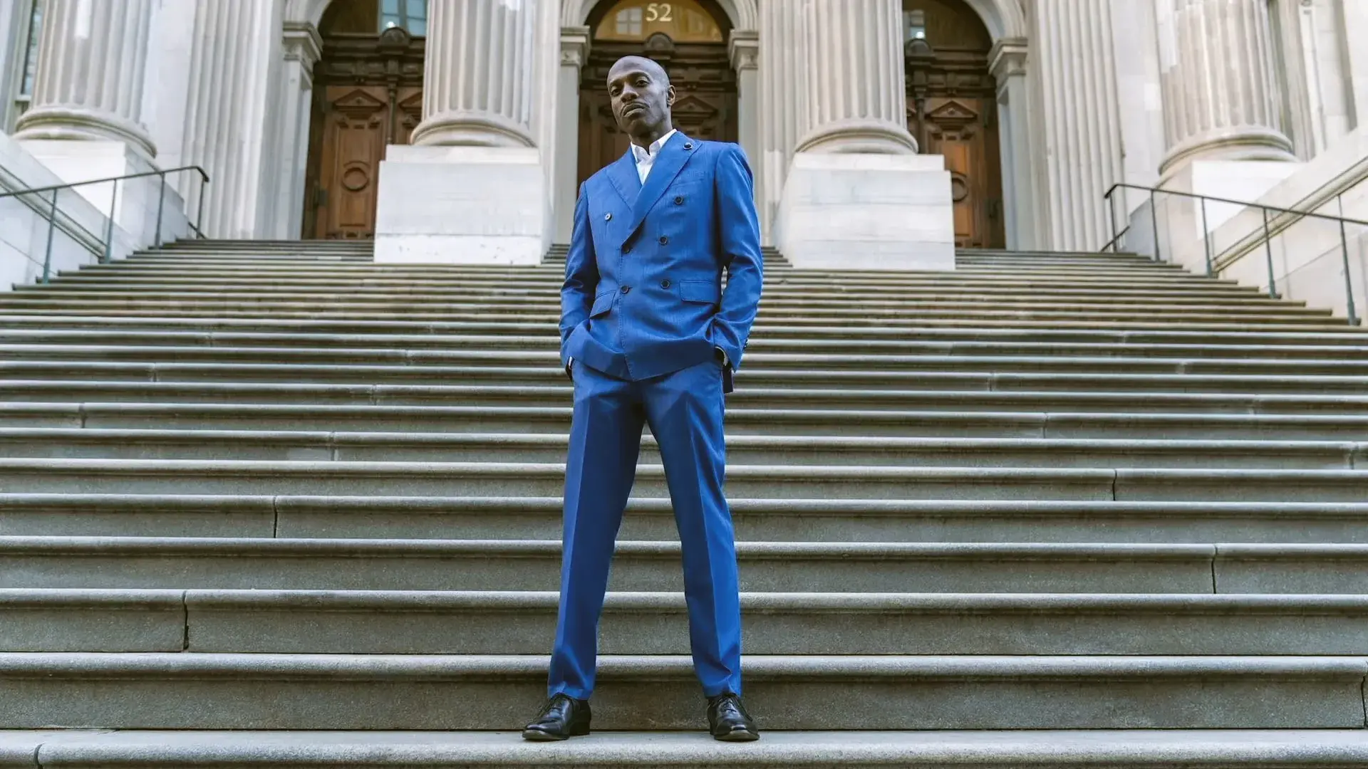 HipHoppreneur Founder and CEO Cedric Muhammad standing confidently on staircase in front of government building.